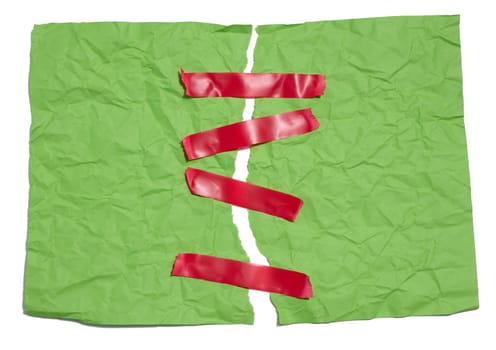 A torn green sheet of paper is fastened with red sticky tape on a white background
