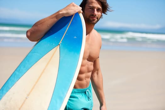 Hes ready to surf. A young man leaning on his surfboard looking at the camera.