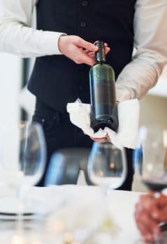 Waiter hands, wine and restaurant table with white towel, luxury hospitality and vintage for fine dining. Man, bottle service and holding drink for customer decision at celebration on valentines day.