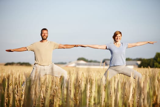 Living a healthy lifestyle together. Portrait of a mature couple enjoying a yoga workout in a crop field.