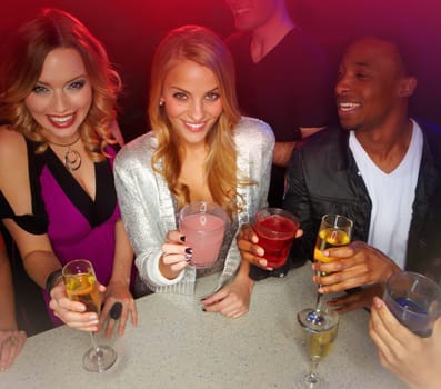 Celebrating good times. A group of friends smiling at the camera while they enjoy drinks in a nightclub - portrait.