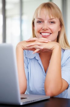 Relaxed business woman with laptop. Portrait of young business woman sitting by desk with laptop.