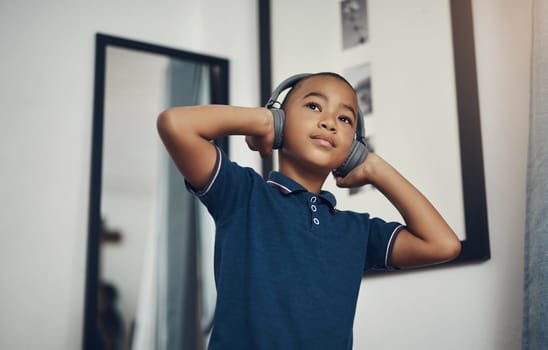 Music enhances their concentration levels. a young boy listening to music through headphones at home.