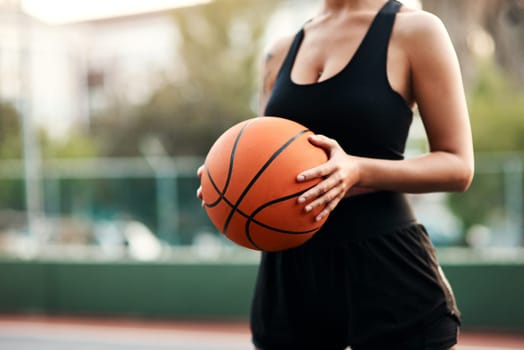 Im ready to play. an unrecognizable sportswoman standing on the court alone and holding a basketball during the day.