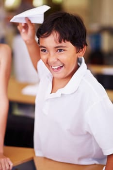 Naughty in class. An indian boy holding a paper airplane in class.