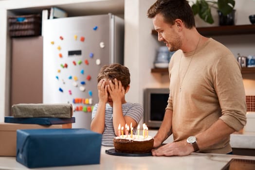 Go ahead and open your eyes now. a man surprising his son with cake and gifts on his birthday.