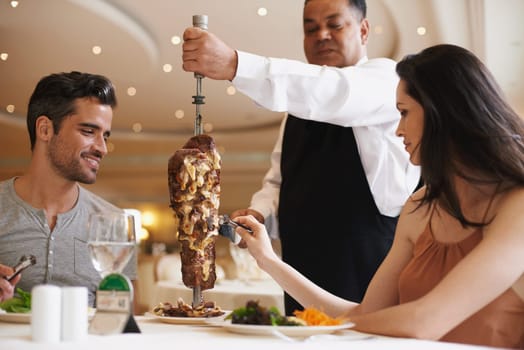 Fine dining with his elegant lady. A happy couple being served a meat dish at a fine dining restaurant.
