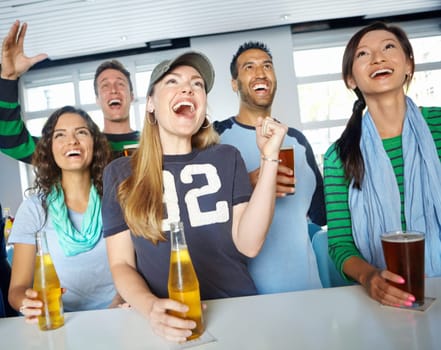 Score. A group of friends cheering on their favourite sports team at the bar.