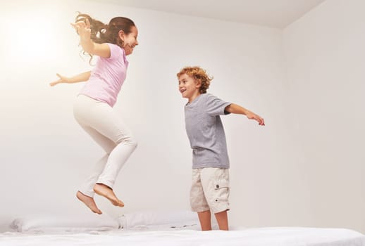 How high can you go. Shot of two little children jumping on a bed.