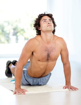 Yoga, man and cobra stretch in home for health, wellness and flexibility in house. Pilates, stretching and male person, yogi or athlete training, holistic workout and exercising for fitness on mat.