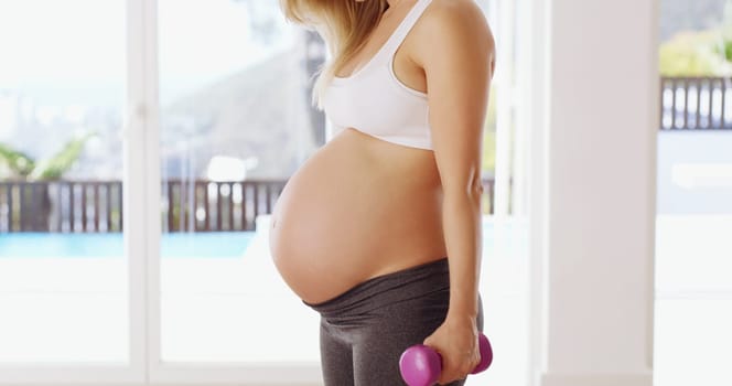 Strong mom = strong baby. Cropped shot of an unrecognizable young pregnant woman working out with dumbbells.
