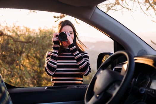woman taking photos with camera during a road trip
