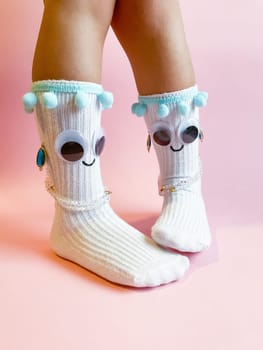 Baby socks with eyes and smile on pink background