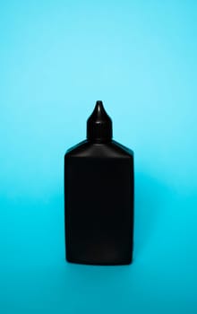 Mock up unbranded black bottle of finish line dry bicycle lubricant with teflon on blue background. Bicycle care, bicycle chain care.