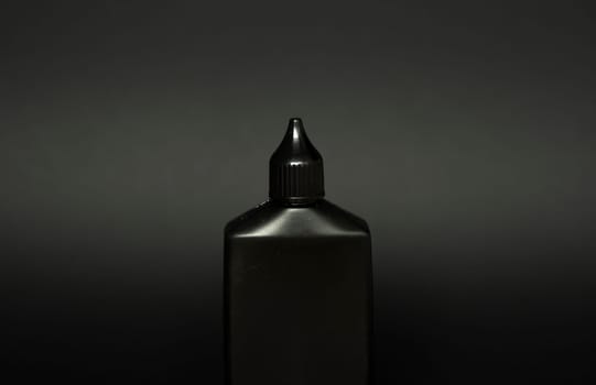 Mock up unbranded black bottle of finish line dry bicycle lubricant with teflon on black background. Bicycle care, bicycle chain care.