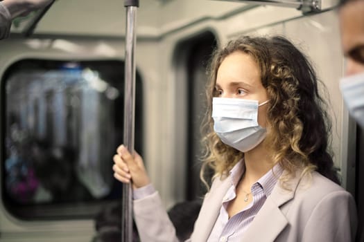 young woman in a protective mask standing in the subway car.