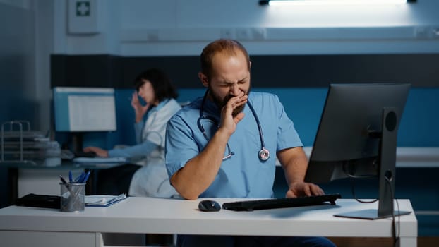 Tired stressed physician nurse working over hours at medical expertise in hospital office