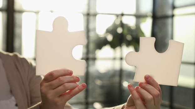 Business Woman holding two blank white puzzle pieces in his hands conceptual of solving a problem, growth and development.