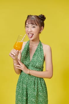 A lovely asian woman in green summer dress, drinking orange juice