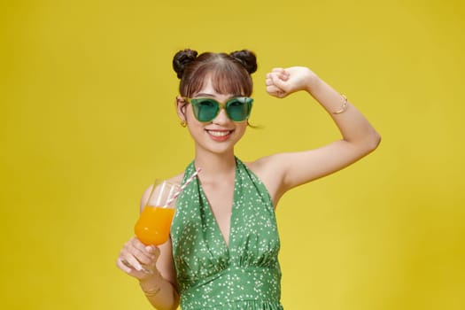 Cute lady holding glass with tropical beverage in hand isolated on bright vivid background