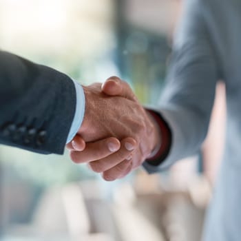 That seals the deal. two unrecognizable businessmen shaking hands after making a deal in the office.