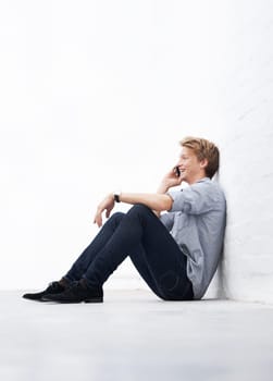 Man, phone call and floor with space by wall with smile, communication and talk at startup. Young businessman, entrepreneur and sitting for conversation on smartphone with mockup at small business.