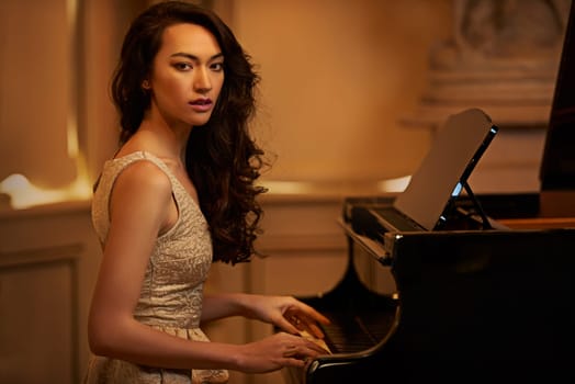 Shell be entertaining you tonight. a beautiful young woman playing the piano in an elegant room.