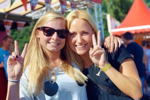 Here to have a rocking time. two women showing the peace sign at a festival.