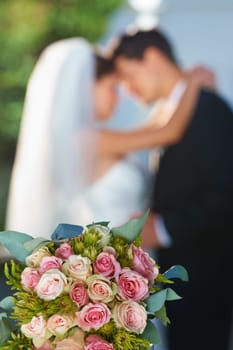 A beautiful floral arrangement. happy newlyweds with focus on a bouquet in the foreground.