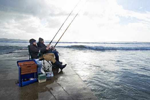 Fishing - Its like shopping for guys. two young men fishing off a pier.