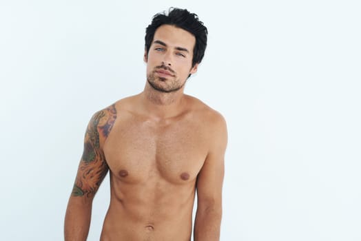 Portrait, body and muscle with a sexy man in studio on a white background for masculine desire. Shirtless, tattoo and manly with a handsome young male model posing topless for rugged sensuality