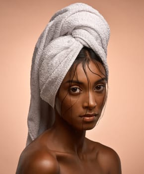 Wrapped up in the pleasures of the world. Portrait of a beautiful young woman with her hair wrapped in a towel against a brown background.