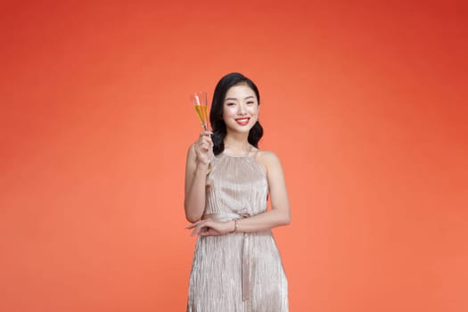Beautiful glamour woman wears elegant dress, holding glass of champagne in hands