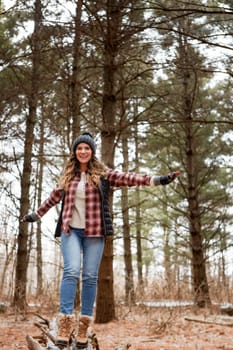 Let hope and optimism flow through you. a young woman walking on a tree log in the wilderness during winter.