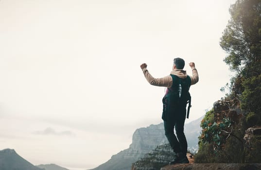 Go where you feel most alive. Rearview shot of a young man standing with his arms outstretched while hiking on a mountain.