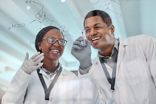 It all makes sense now. two scientists drawing molecular structures on a glass wall in a lab.