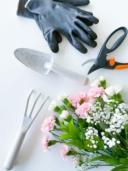 spray pink and white flowers with gardening tools