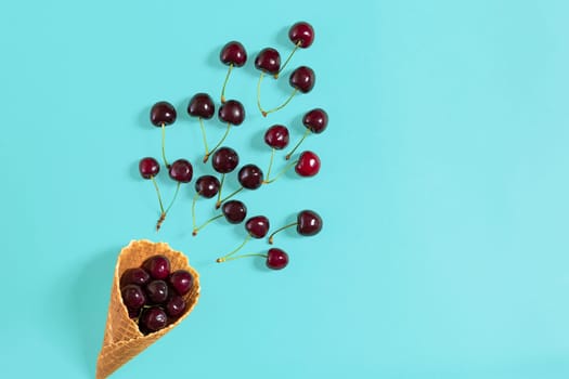 Cherries in waffle cone on blue background. Top view.