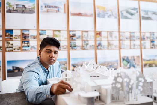 The king of contemporary architecture. a young architect designing a building model in a modern office.