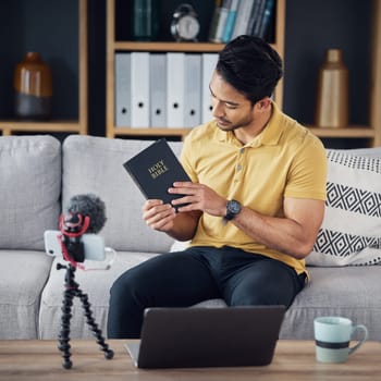 Christian man, bible and study with phone and microphone online while live streaming. Asian male on home sofa with holy book on religion as blog content creator or influencer teaching on podcast.