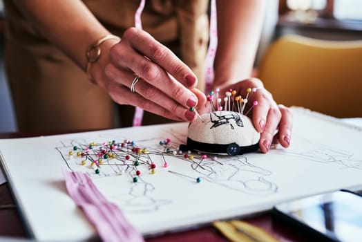 The fashion industry is full of color and creativity. an unrecognizable designer using a pincushion while working in her workshop.