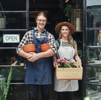 Another day, another sale. Cropped portrait of two young business owners standing at the entrance of their floristry together and holding potting supplies.
