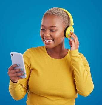 Search, phone and music with black woman in studio for streaming, multimedia and browsing. Gen z, smile and audio with female and headphones on blue background for listening, online radio and songs