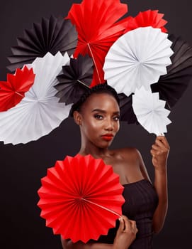 Make your style as vibrant as your personality. Studio shot of a beautiful young woman posing with a origami fans against a black background.