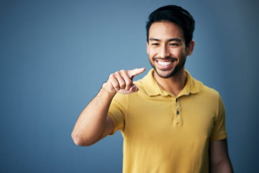 Mockup, smile and Asian man pointing, space and product placement against blue studio background. Japan, male and happy guy with brand development, happiness and suggestion with promotion and choice