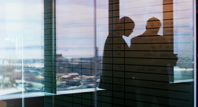 Making decisions as a team. Silhouette shot of two businesspeople having a discussion inside an office building.