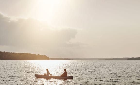Great idea to getaway on the lake. an unrecognizable couple rowing a boat out on the lake.