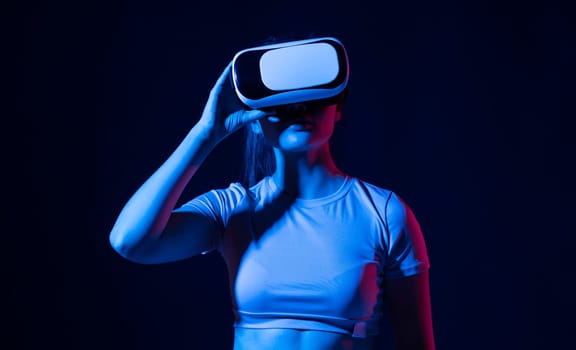 Woman using VR virtual reality glasses headset pointing at objects in metaverse. Virtual reality metaverse.