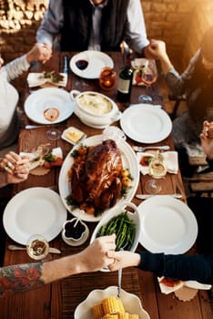 Were grateful for the food were about to eat. High angle shot of an unrecognizable family saying grace at the dining table on Thanksgiving.