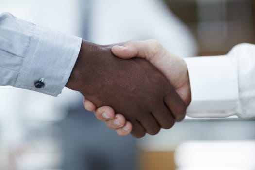 Business partners - Sealing the deal. Close up of a handshake between an African businessman and a Caucasian businessman.